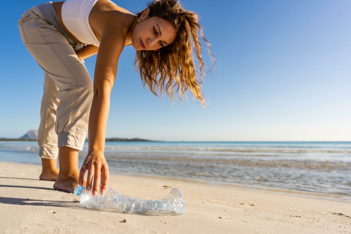 vrouw-raapt-plastic-fles-van-strand