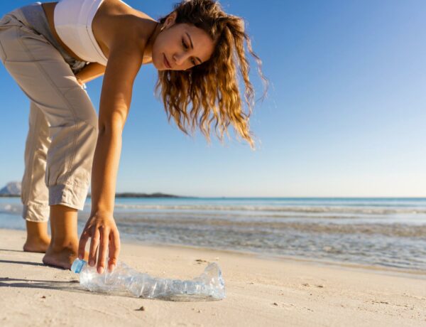 vrouw-raapt-plastic-fles-van-strand