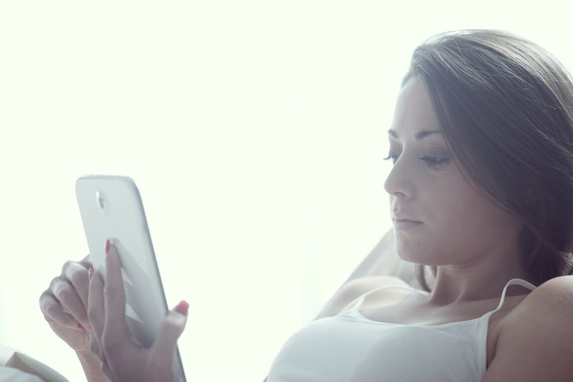 vrouw-ligt-in-bed-met-tablet-social-media-verslaving