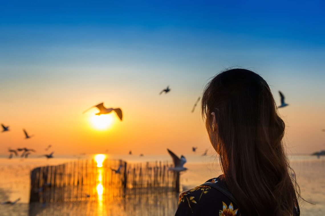 Vrouw-kijkt-naar-zonsondergang-bij-zee